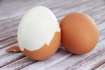 Peeled boiled egg on wooden background