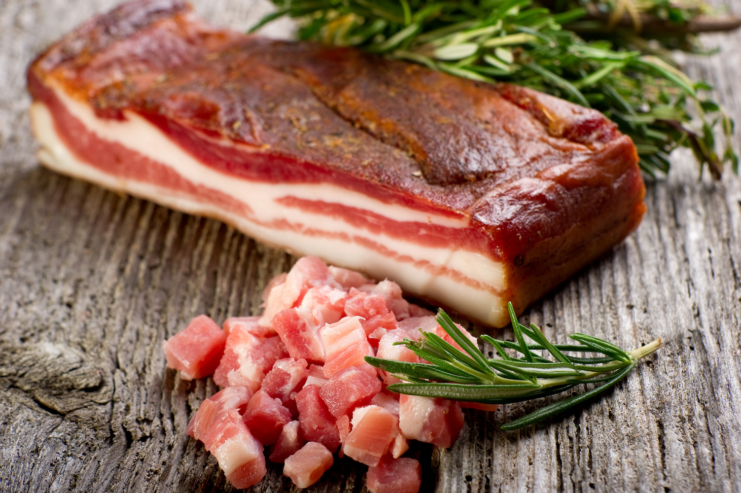 fresh bacon with rosemary on wood background
