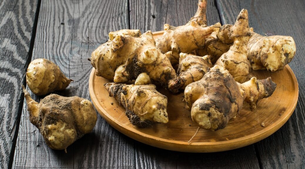 Fresh Jerusalem artichokes on wooden background