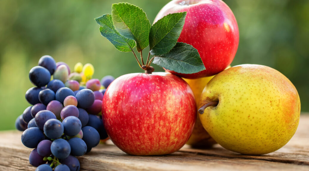 Red apple, pear, grapes on wooden table
